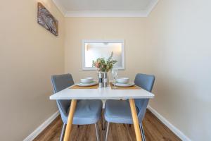 a dining room with a white table and blue chairs at Grange Studio Apartment - Heathrow in London