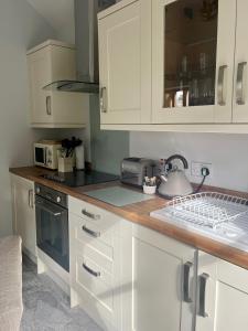 a kitchen with white cabinets and a tea kettle on the counter at Fern Cottage in Lynton
