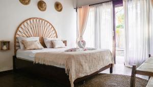 a bedroom with a large bed and a large window at VILLA MENORCA in Gili Trawangan