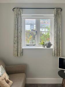 a living room with a window with curtains and a couch at Fern Cottage in Lynton