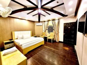 een slaapkamer met een bed en een tafel en een televisie bij Hotel Visit Inn Executive in Lahore
