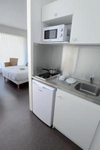 a kitchen with a stove and a microwave in a room at Hotel Thermes Les Ecureuils in Dax