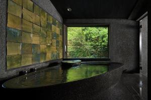 een badkamer met een groot bad en een raam bij Ryokan Sumiya Kihoan in Kameoka