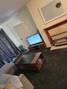 a living room with a flat screen tv and a table at Warm Contractor-Friendly Home in Luton +6 photos