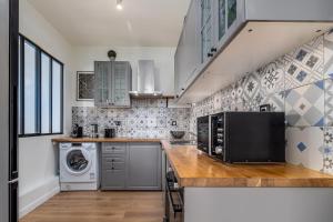 a kitchen with a microwave and a washer and dryer at Berge - Appartement proche Disneyland Paris in Meaux