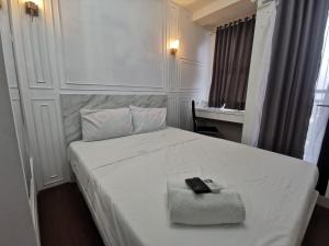 um quarto com uma cama branca com dois controlos remotos em ARSAKHA 003 Transpark Cibubur By Karlina em Kalimanggis