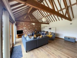 un soggiorno con divani blu e un muro di mattoni di Charming Norfolk Barn Conversion in Barnham Broom a Norwich