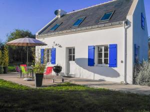 Biały dom z niebieskimi okiennicami i parasolem w obiekcie Maison Neuve Confortable Proche Plages à Locmaria – Jardin, Terrasse, Wifi, Classée 3* - FR-1-418-209 w mieście Locmaria