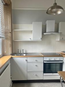 una cocina con armarios blancos y fregadero en Pebbles, en Lynton