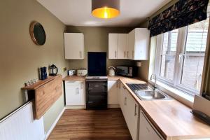 a kitchen with white cabinets and a black refrigerator at Gorgeous Two Bedroom House in Ely in Ely