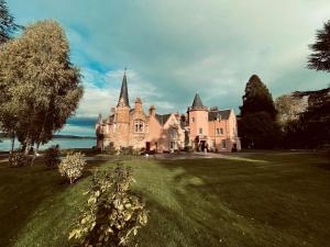 an old castle on a field of grass with a tree at Bunchrew House Hotel in Inverness
