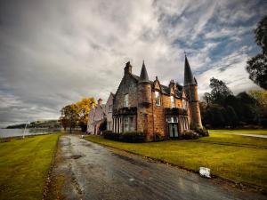 una casa vieja con una torreta al lado de una carretera en Bunchrew House Hotel, en Inverness