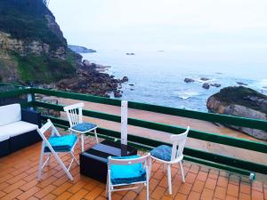 3 sillas y un sofá en un balcón con vistas al océano en LA TERRAZA DE PLAYA ESTAÑO, en Gijón