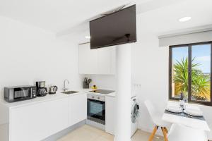 biała kuchnia ze stołem i oknem w obiekcie MEDANO4YOU White Dream Penthouse w mieście El Médano
