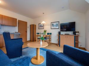 ein Wohnzimmer mit einem Tisch und blauen Stühlen in der Unterkunft Dünenpark Binz - Komfort Ferienwohnung mit 1 Schlafzimmer und Balkon im Dachgeschoss 293 in Binz