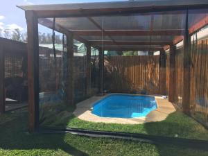 una piscina bajo una pérgola de madera en Hermosa casa con piscina climatizada entre el mar y las sierras en Bella Vista - Piriápolis, en Bella Vista