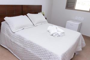 Una cama blanca con dos toallas encima. en Pousada Carlitos, en Iturama