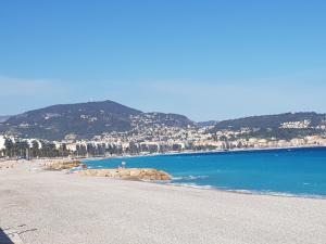 una playa de agua azul y edificios y montañas en Grand studio de 30 m2 Promenade des Anglais en Niza