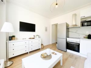a kitchen with white cabinets and a white table at Studio bord de mer 3 in Menton