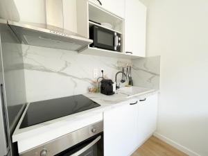 eine weiße Küche mit einer Spüle und einer Mikrowelle in der Unterkunft Studio bord de mer 3 in Menton