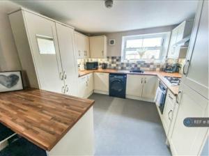 a large kitchen with white cabinets and a refrigerator at Freedom Hall Apartment in Queensbury