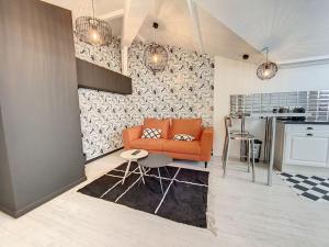 a living room with an orange couch and a kitchen at Bienvenue à la Tatoo Room in Bourgoin