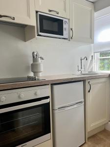 a white kitchen with a microwave and a sink at Beachglass in Lynton