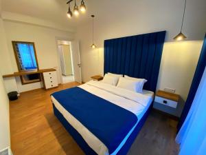 Schlafzimmer mit einem großen Bett mit blauem Kopfteil in der Unterkunft City Heart Luxury Apartment in Kutaissi