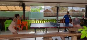 a group of people standing around a ping pong table at Pinaluyan Guest House in Puerto Princesa City