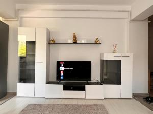 una sala de estar con TV y un centro de entretenimiento blanco en 2 rooms apartment Airy & Bright Relax, en Iaşi