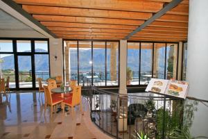 ein Esszimmer mit einem Tisch, Stühlen und Fenstern in der Unterkunft Village Hotel Lucia in Tremosine sul Garda