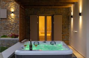 a hot tub with two glasses of wine in it at Quinta Essentia Suites in Foiníki
