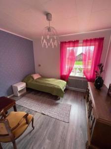 1 dormitorio con cama verde y cortinas rosas en Ödeshög Modernt och stilfullt B&B, en Ödeshög