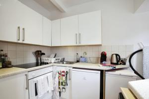 eine weiße Küche mit weißen Schränken und Geräten in der Unterkunft Charming West London Studio Your Urban Oasis in London