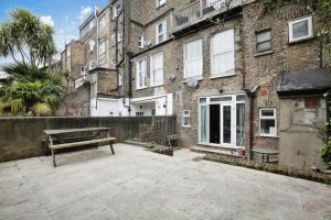 eine Bank auf einer Terrasse vor einem Gebäude in der Unterkunft Charming West London Studio Your Urban Oasis in London