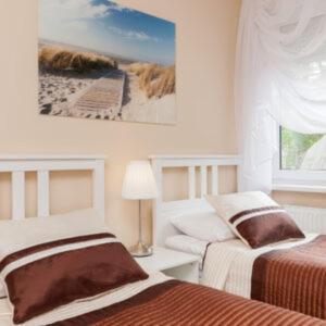 a bedroom with two beds and a picture of a beach at Villa Puerto in Pobierowo