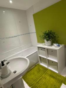 a bathroom with a white sink and a tub and a plant at Cozy Homestay in Croydon