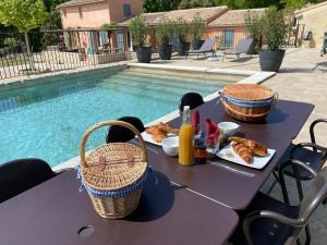a picnic table with food next to a swimming pool at Les micocouliers in Lagnes