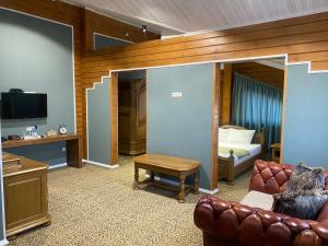 Sala de estar con sofá, cama y TV en Guest House Chalet en Taraz