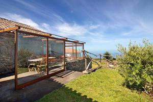 una casa in vetro con tavolo e vista sull'oceano di Villa Montemar a Calheta