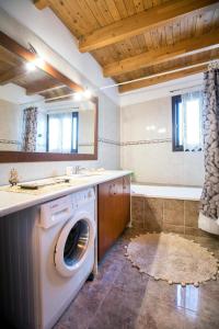 a washing machine in a bathroom with a sink and a tub at Villa Rafaela in Koskinou