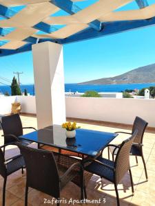 a table and chairs on a patio with a view of the ocean at Zafeiris Apartments in Livadia