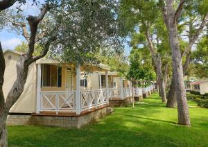 una fila de casas móviles en un patio con árboles en Green Garden Village, en Sirolo