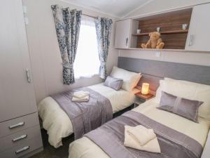 um quarto com 2 camas e um urso de peluche numa janela em Buttercup Lodge em Saltburn-by-the-Sea
