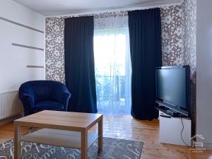 a living room with a tv and a blue chair and a table at Apartamentai Biržuose, double bedroom and single bedroom Apartments in Biržai