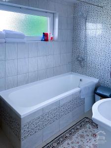 a white bathroom with a tub and a window at Apartamentai Biržuose, double bedroom and single bedroom Apartments in Biržai