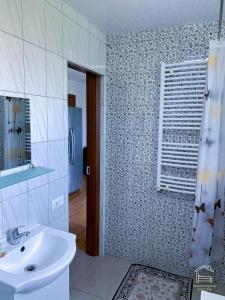a bathroom with a white sink and a shower at Apartamentai Biržuose, double bedroom and single bedroom Apartments in Biržai