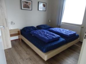 a bedroom with a bed with blue pillows on it at Kustverhuur, Oude manege Nieuwvliet, Nieuwvliet 1 - 2 in Nieuwvliet