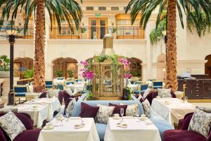 un restaurante con mesas, sillas y palmeras en The Landmark London en Londres