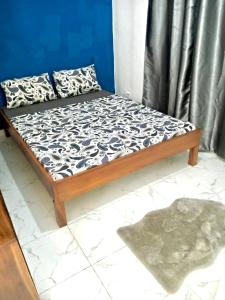 a bed in a room with a blue wall at Gêna house in Douala